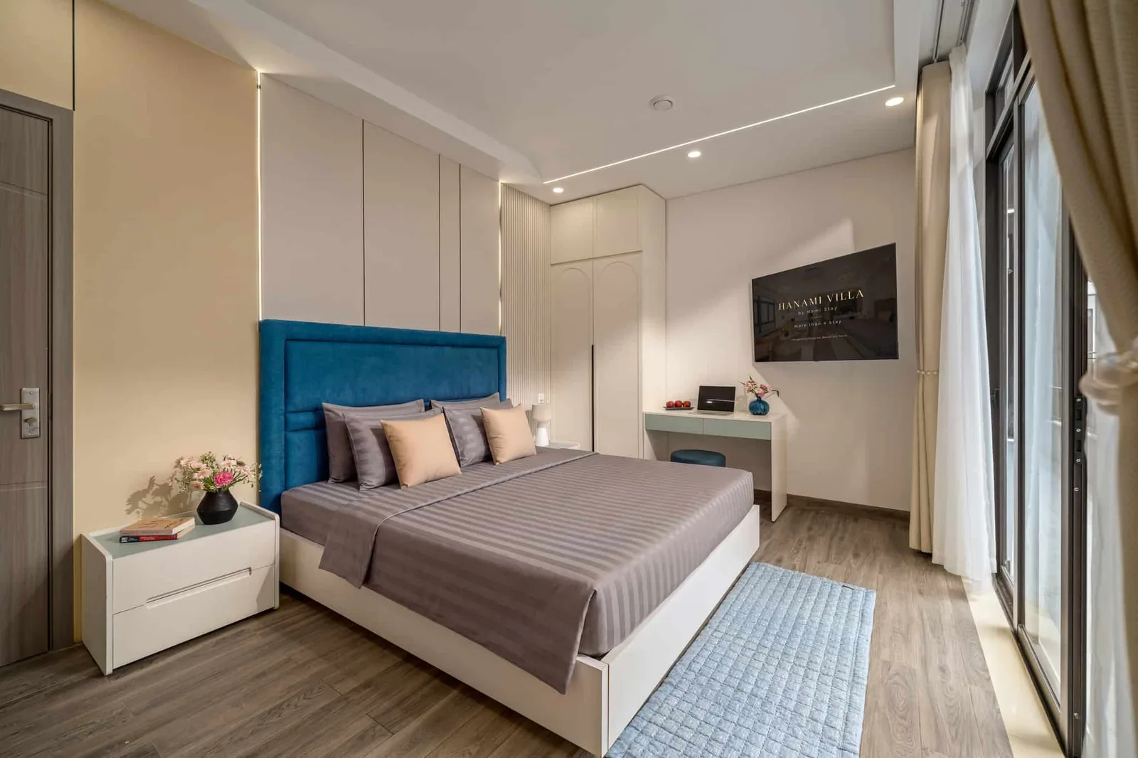 Phòng ngủ với một giường lớn, bàn đầu giường và cửa kính.